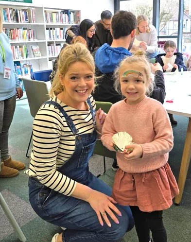 Becky helping a child make a recycled book craft at Shenfield Library
